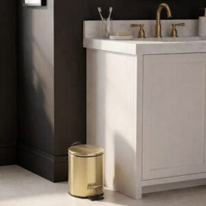 Gold trash can in bathroom corner next to vanity cabinet
