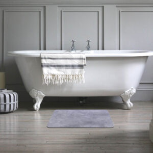 Classic white clawfoot bathtub with a stylish concrete diatomite bath mat placed on a wooden floor