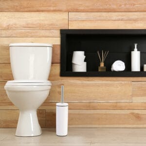 a white toilet brush set next to toilet seat in bathroom environment