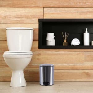 Chrome metal trash can next to toilet in modern bathroom