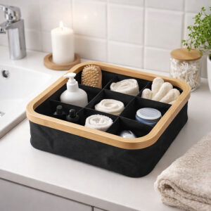 Image 2: Black bamboo-rimmed 9-compartment basket holding toiletries, rolled towels, and a loofah on a white bathroom countertop.
