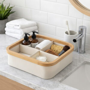 Ecru bamboo-rimmed 4-compartment basket holding toiletries, soaps, a comb, and a makeup brush on a marble bathroom countertop.