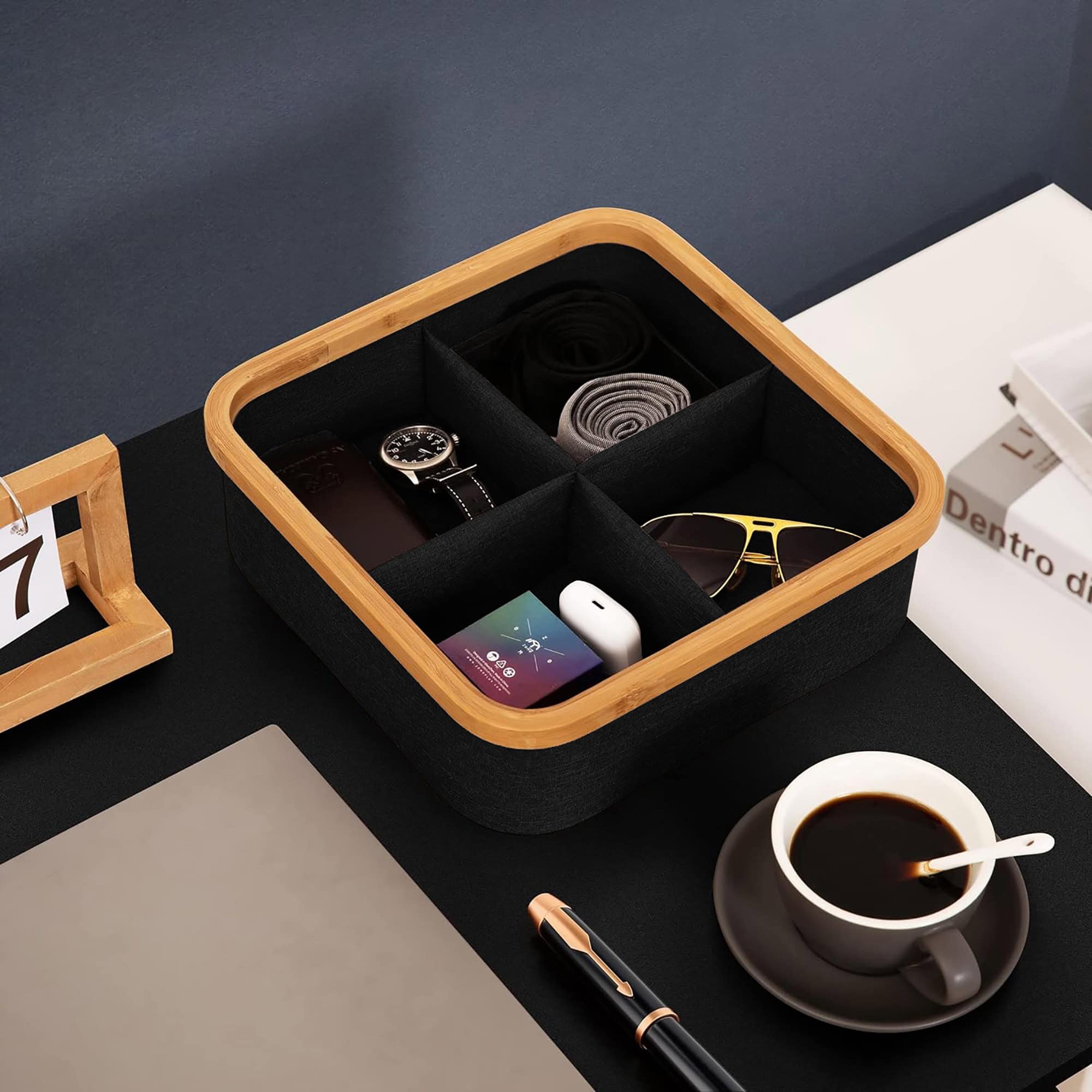 Black bamboo-rimmed 4-compartment basket organizing a watch, sunglasses, earbuds, and accessories on a dark desk.