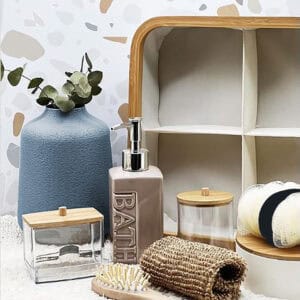 Close-up of an ecru fabric 4-compartment storage basket with bamboo rim, styled with bathroom accessories including a soap dispenser and cotton jars.