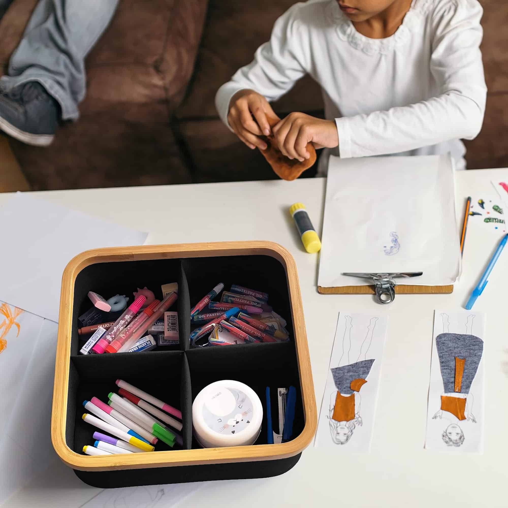 Black Oxford fabric 4-compartment storage basket with bamboo rim, holding art supplies and markers on a child's craft table.
