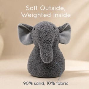 Grey elephant door stopper on a tan background with a callout line. On-image text: "Soft Outside, Weighted Inside," "90% sand, 10% fabric."