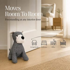 Charcoal dog door stopper propping open a white door, with icons for four rooms. On-image text: "Moves Room To Room," "Freestanding at any interior door," "Living Room," "Bedroom," "Office," "Nursery."