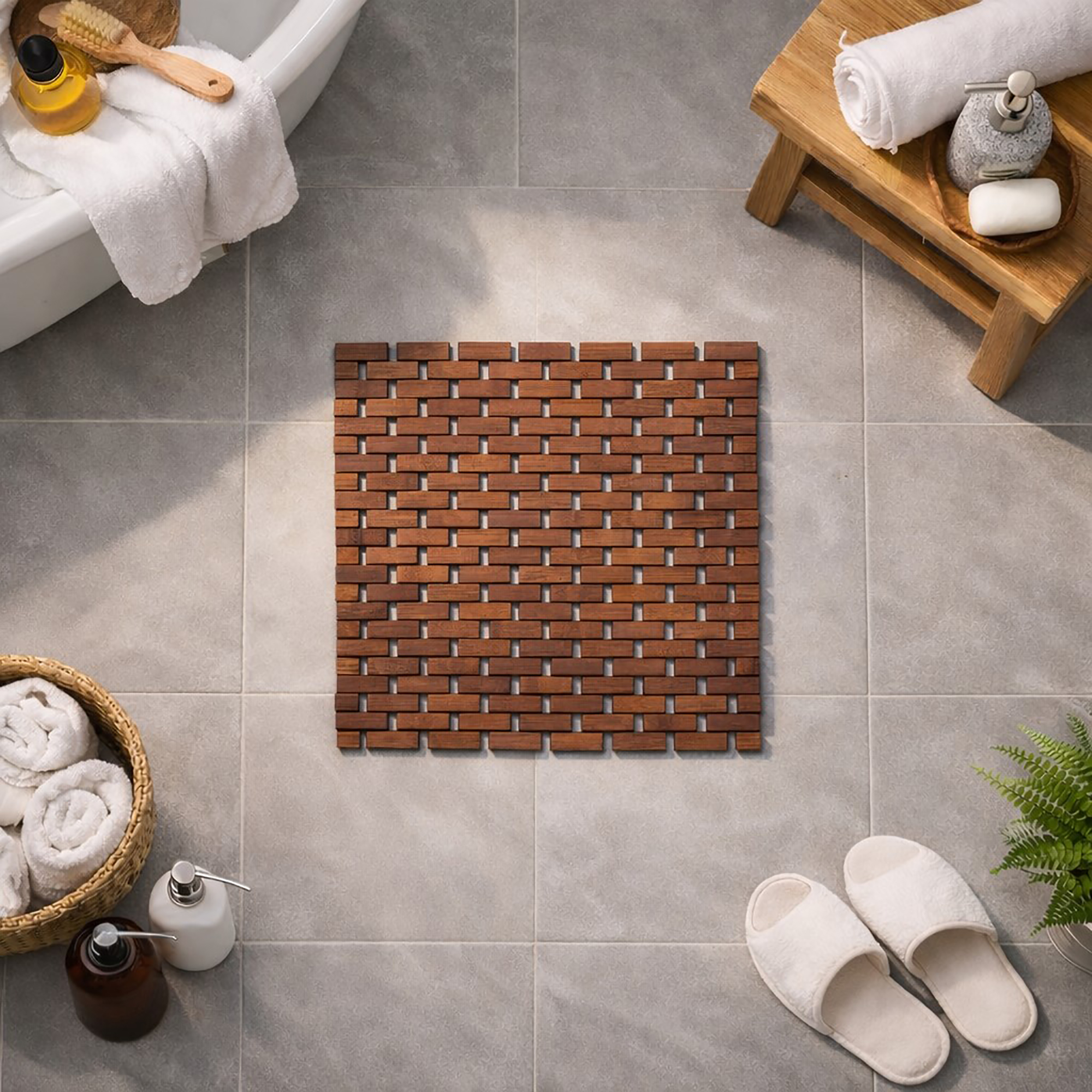 Bamboo bath mat with woven basketweave pattern on gray tile floor surrounded by spa accessories