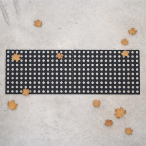 "Two interlocked black rubber open-grid mats forming a wide runner on concrete, surrounded by fallen autumn leaves"
