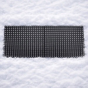 Two interlocking black rubber ring mats connected side by side, surrounded by snow.