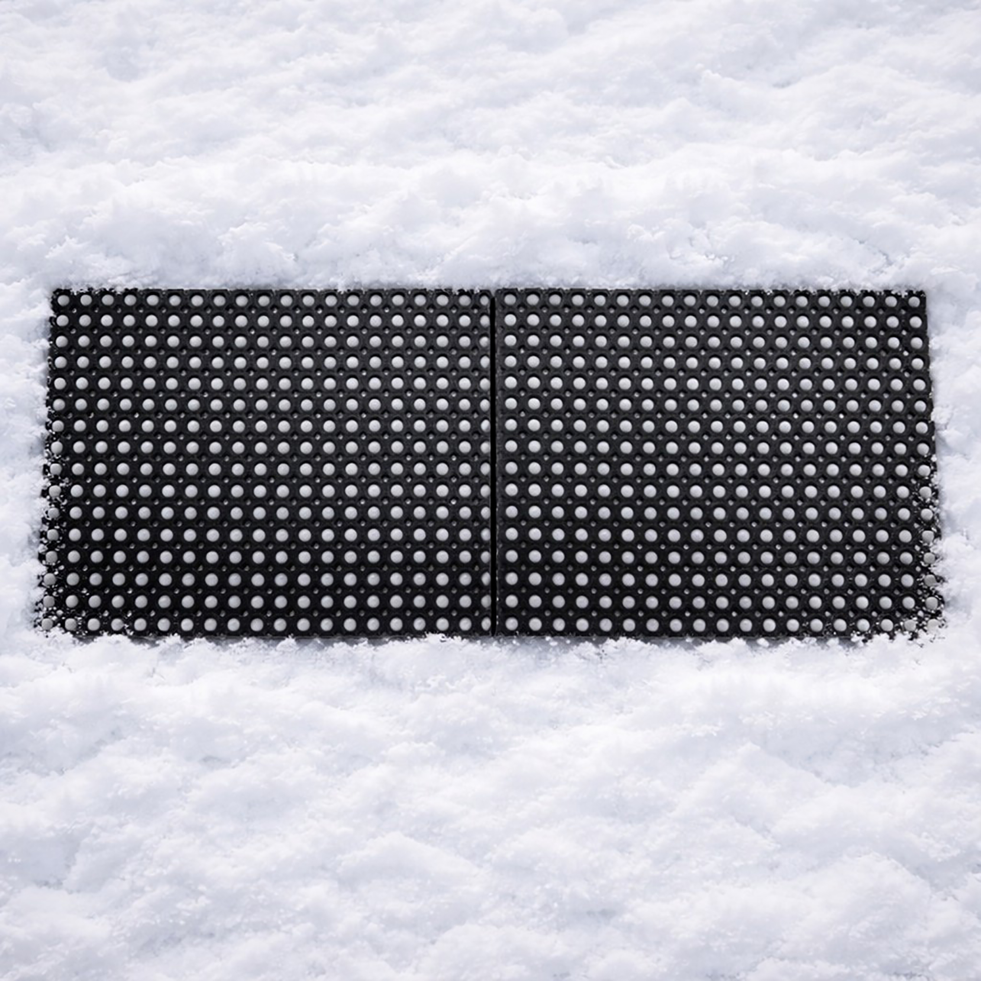 Two interlocking black rubber ring mats connected side by side, surrounded by snow.