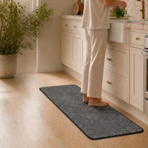Bare feet resting on a cushioned charcoal grey kitchen runner, highlighting the soft comfort of the two-piece set underfoot.
