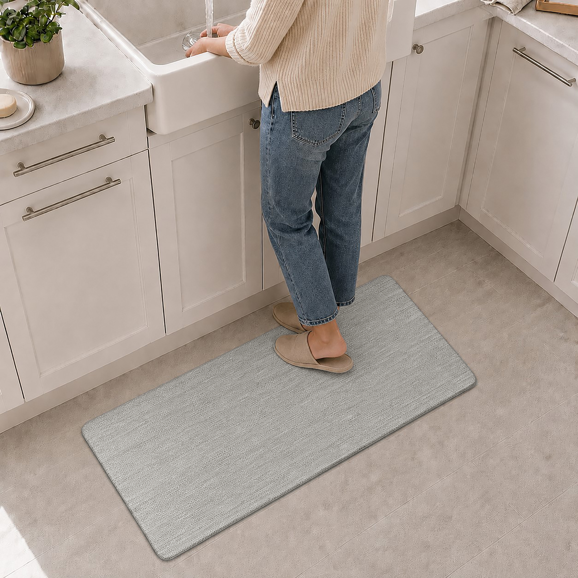 7- Person standing on gray anti-fatigue kitchen mat at the sink, cushioned comfort underfoot while washing up.
