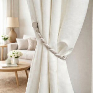 Beige braided magnetic tieback holding white curtain, living room setting