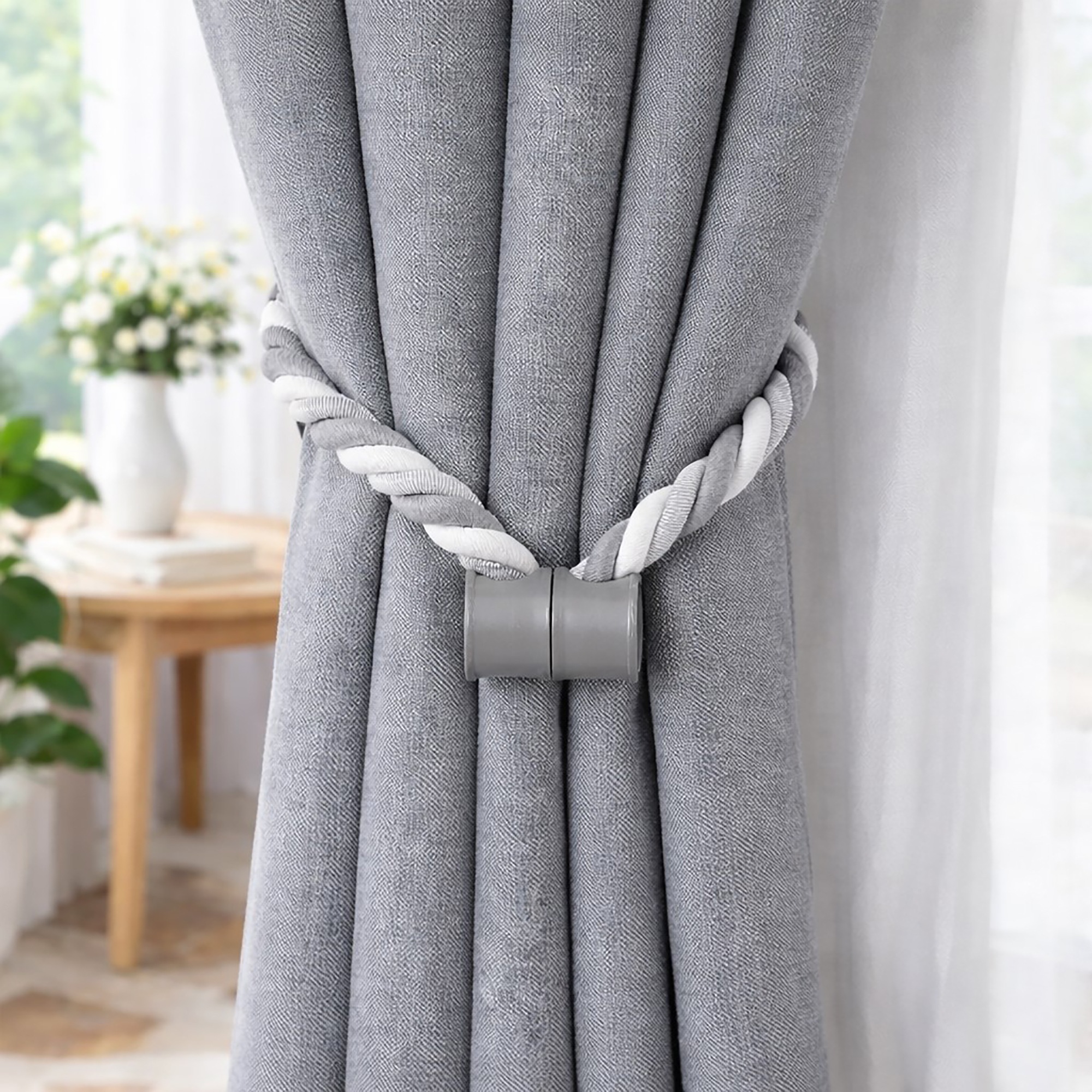 Gray braided magnetic tieback holding blue curtain, magnetic clasp visible
