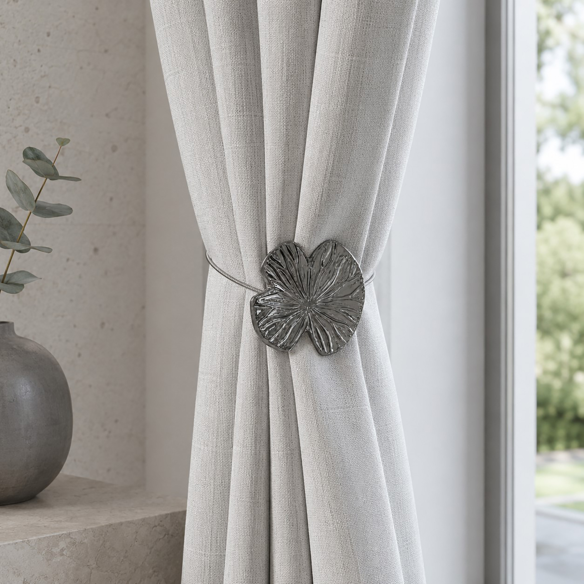 Lifestyle minéral: Polished graphite water lily curtain tieback on a light linen curtain in a minimal stone-toned room