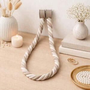 Beige braided tieback displayed on wooden surface with candle and flowers