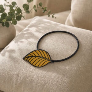 Yellow leaf tieback resting on a linen cushion with eucalyptus accent