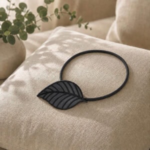 Gray leaf tieback resting on a linen cushion with eucalyptus accent