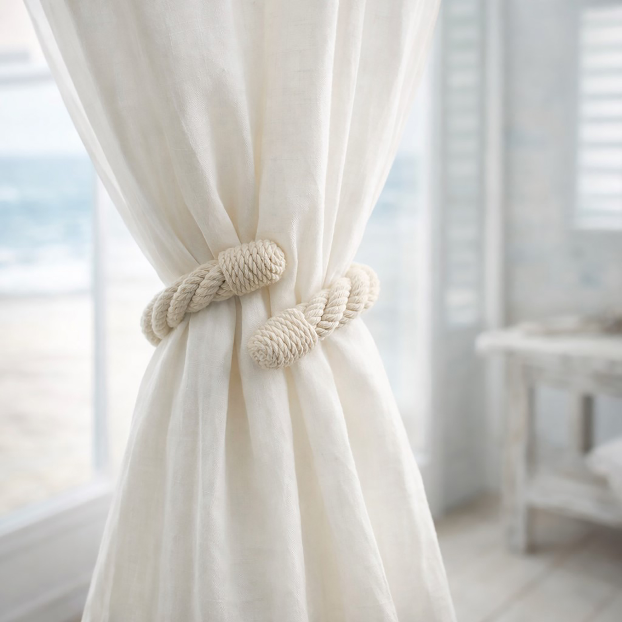 "Ecru cotton rope tieback securing a sheer curtain in a coastal-style room"