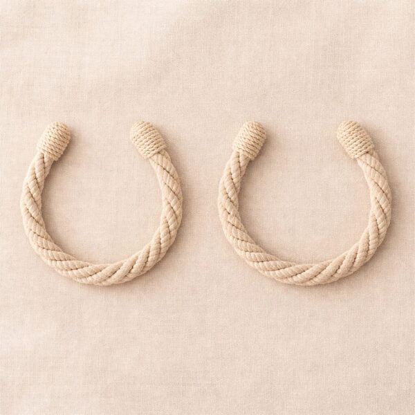 "Ecru twisted rope tiebacks in U-shape on fabric surface"
