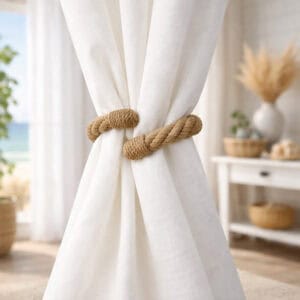 "Jute rope tieback securing white curtain panels in a coastal-style room"