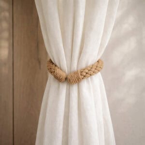 "Jute rope tieback wrapped around a gathered sheer curtain against a wood-toned wall"