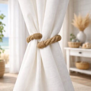 "Jute rope tieback securing white curtain panels in a coastal-style room"