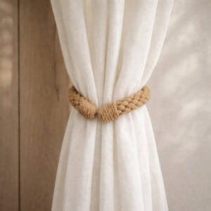 "Jute rope tieback wrapped around a gathered sheer curtain against a wood-toned wall"