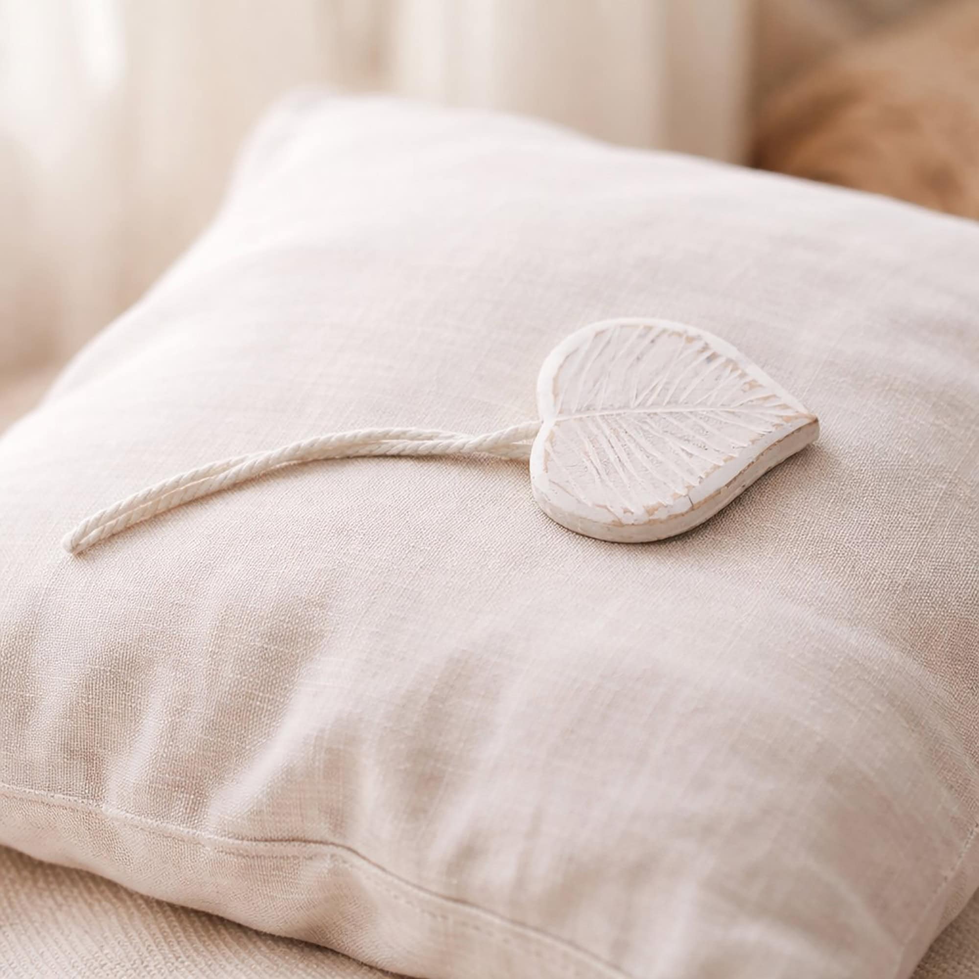 White carved wooden leaf tieback on linen cushion