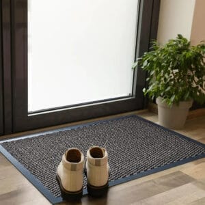 Tan entry door mat with rubber border placed indoors with shoes
