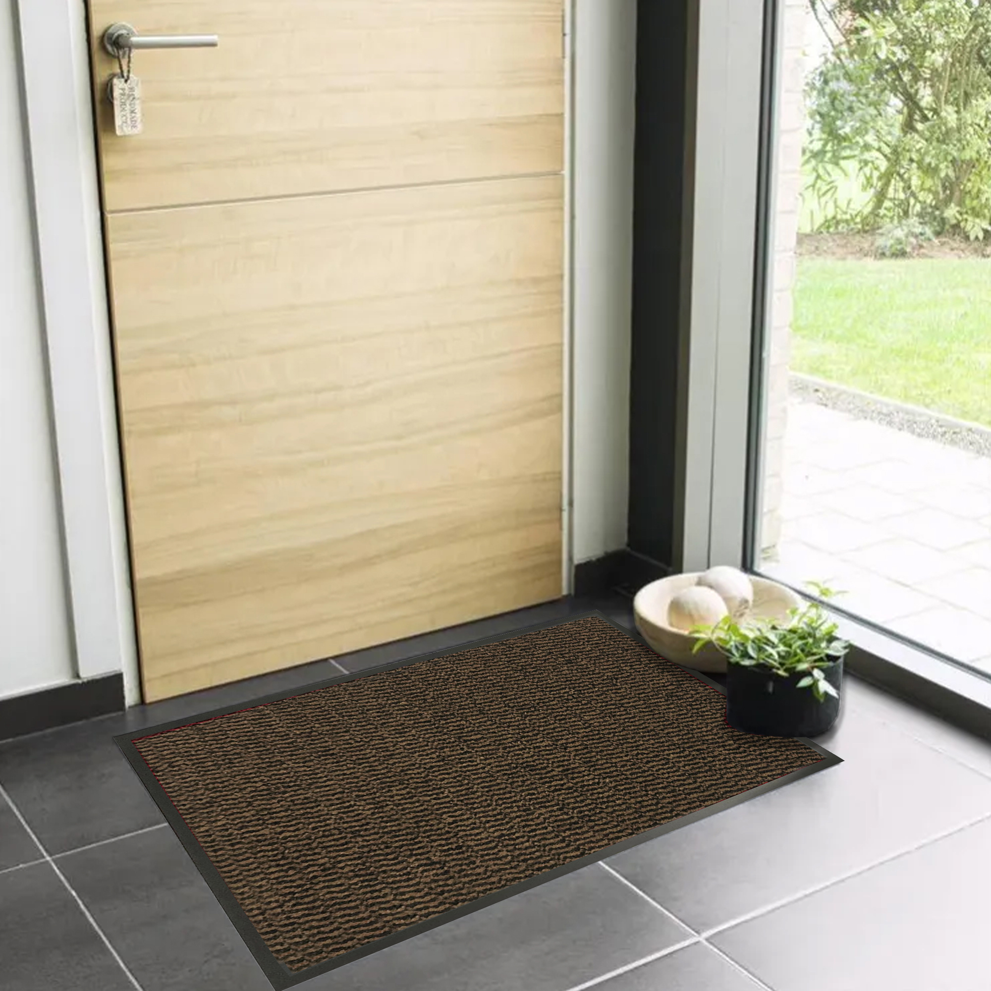 Tan indoor entryway mat with low profile design near wooden door