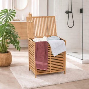 Bamboo slatted laundry hamper with lid open and towels inside, in a modern bathroom with glass shower and monstera plant