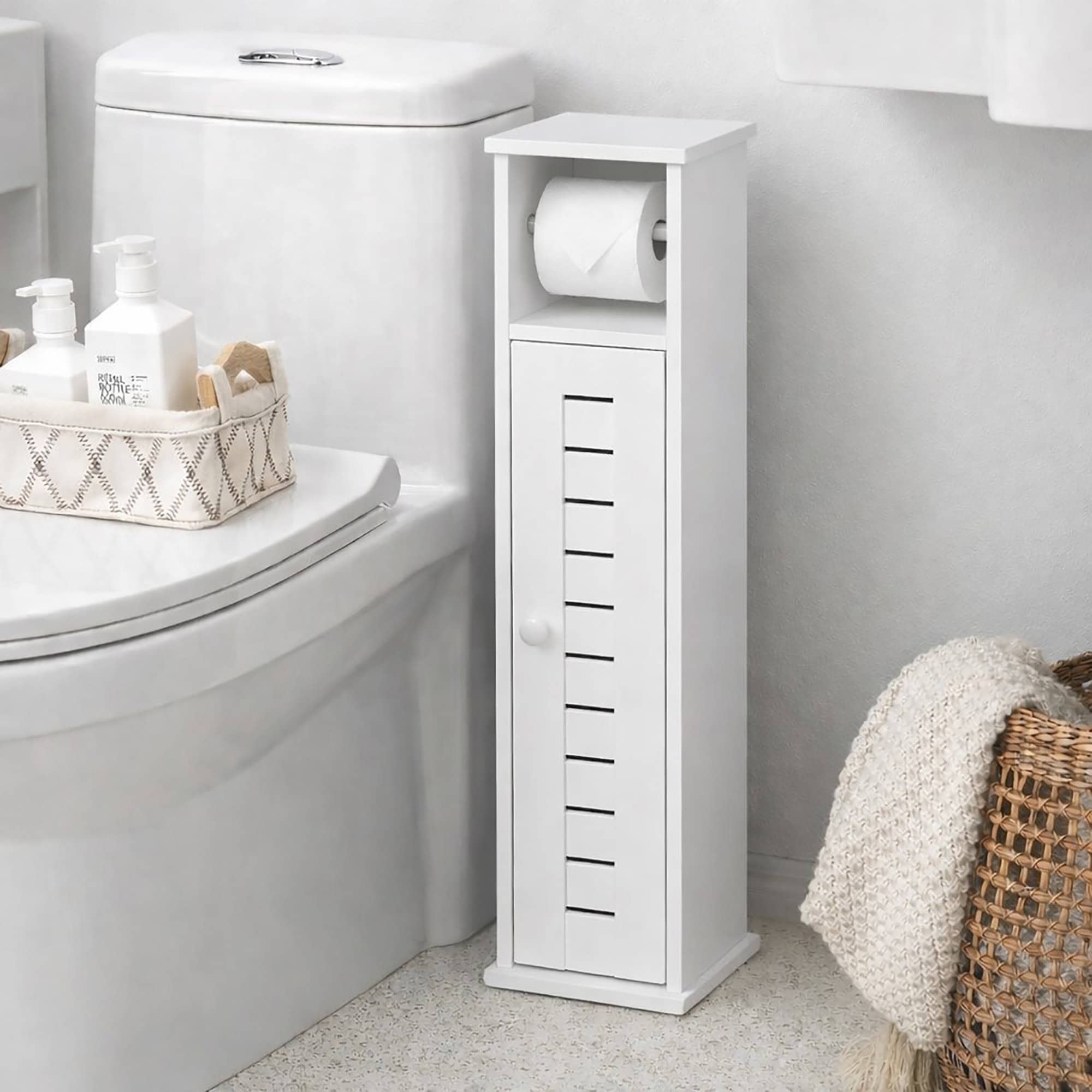 "White narrow toilet paper storage cabinet with roll holder and round knob louvered door, placed beside a toilet"