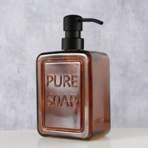 Stylish Amber Glass Soap Dispenser for Bathroom Decor on a Light Gray Background – An amber glass soap dispenser with a black pump, elegantly showcased on a light gray background, adding a sophisticated touch to bathroom decor.
