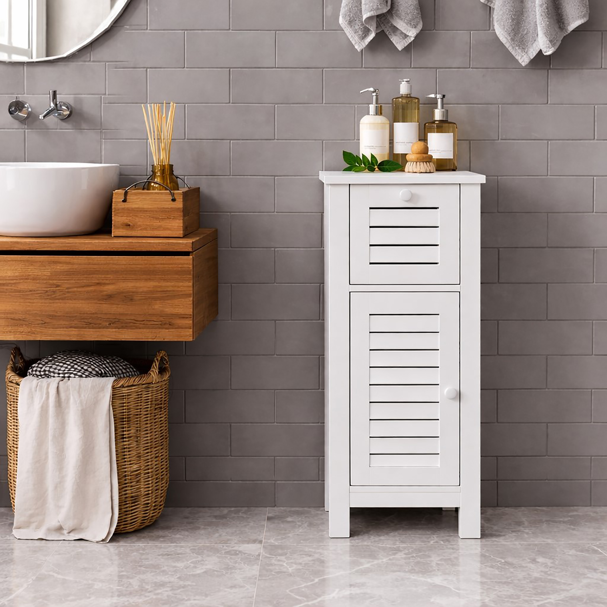 "White louvered floor cabinet topped with toiletry bottles, styled beside a wood-floating vanity and grey subway tile wall"