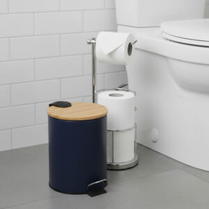 Navy blue step trash can with bamboo lid next to toilet