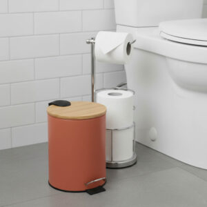 Terracotta step trash can with bamboo lid next to toilet