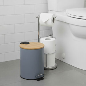 Gray step trash can with bamboo lid next to toilet