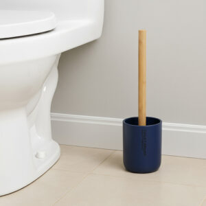 Navy blue toilet brush with bamboo handle in matching holder placed beside toilet