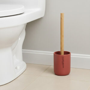 Terracotta toilet brush with bamboo handle in matching holder placed beside toilet