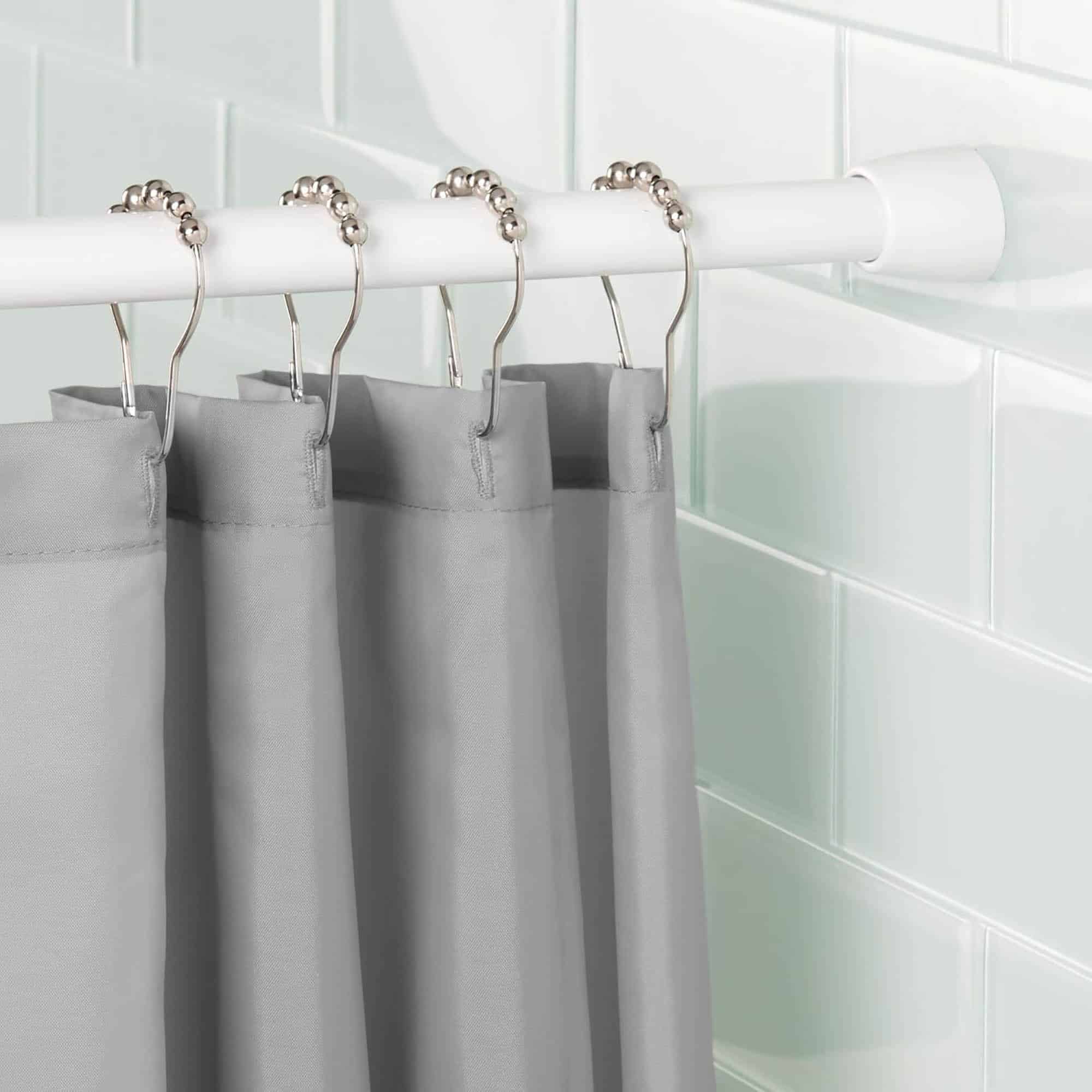 Shower Rod Display with Gray Curtain and Rings in Modern Bathroom: A white shower curtain rod installed in a modern bathroom, holding a gray curtain with decorative metal rings.