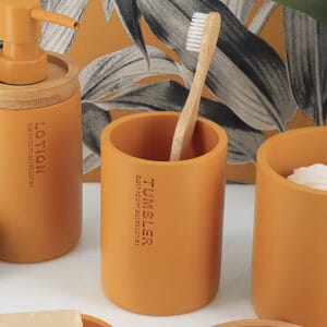 Toothbrush holder in a mustard yellow finish with bamboo accents in the background