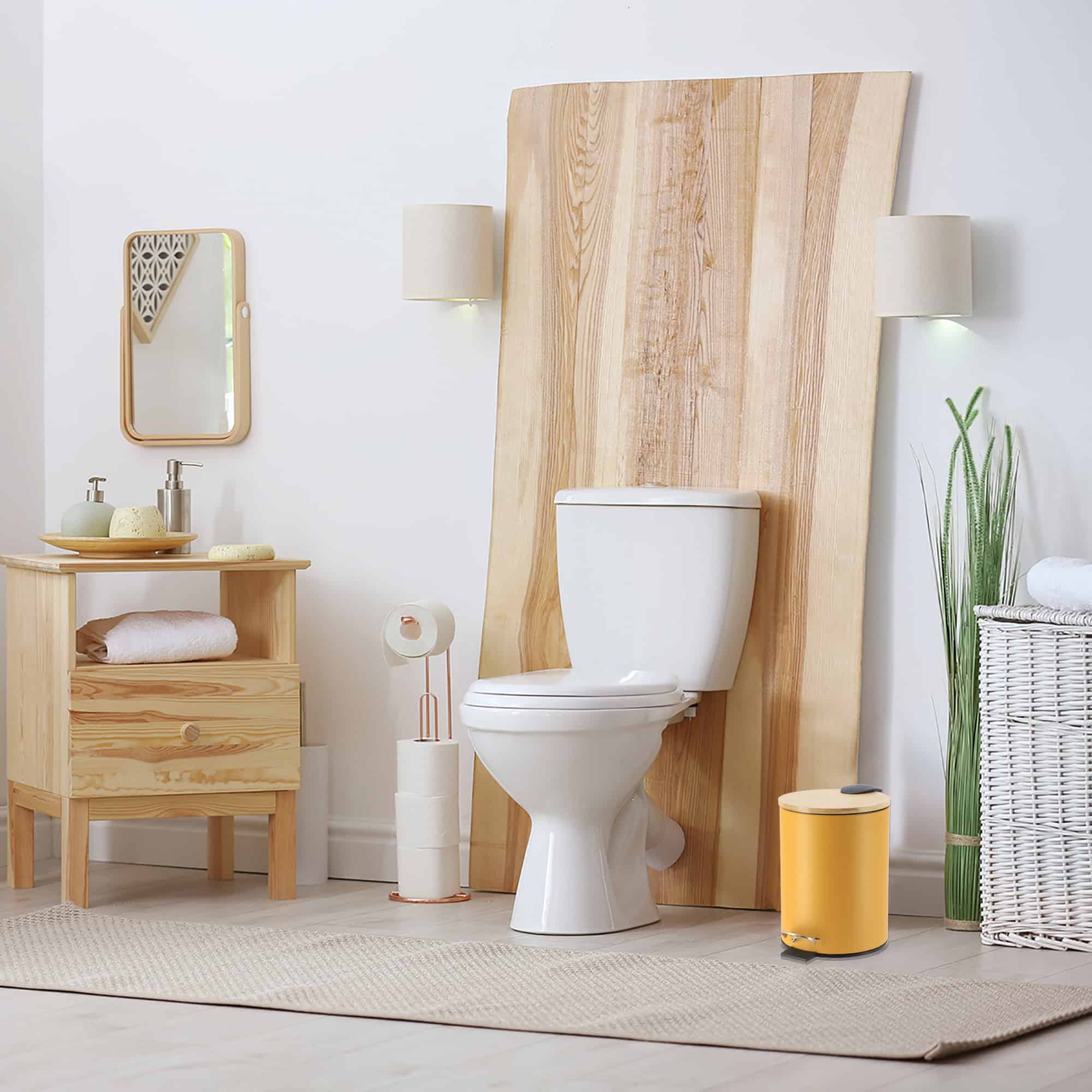 A mustard yellow step trash can with a bamboo lid placed in a bathroom with natural wood accents, complementing the serene and modern décor.