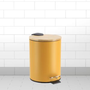 A mustard yellow step trash bin with a bamboo lid and soft-close feature, placed in a tiled bathroom setting.