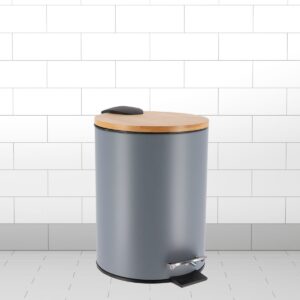 Gray trash bin with bamboo lid and pedal, styled against a white tiled wall.