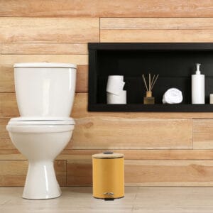 A minimalist bathroom with wooden paneling featuring a yellow step trash can with a bamboo lid, adding a touch of style and functionality.