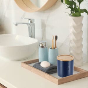 Navy blue cotton jar with bamboo lid styled on a bathroom tray, surrounded by matching accessories and a minimalist sink setup.