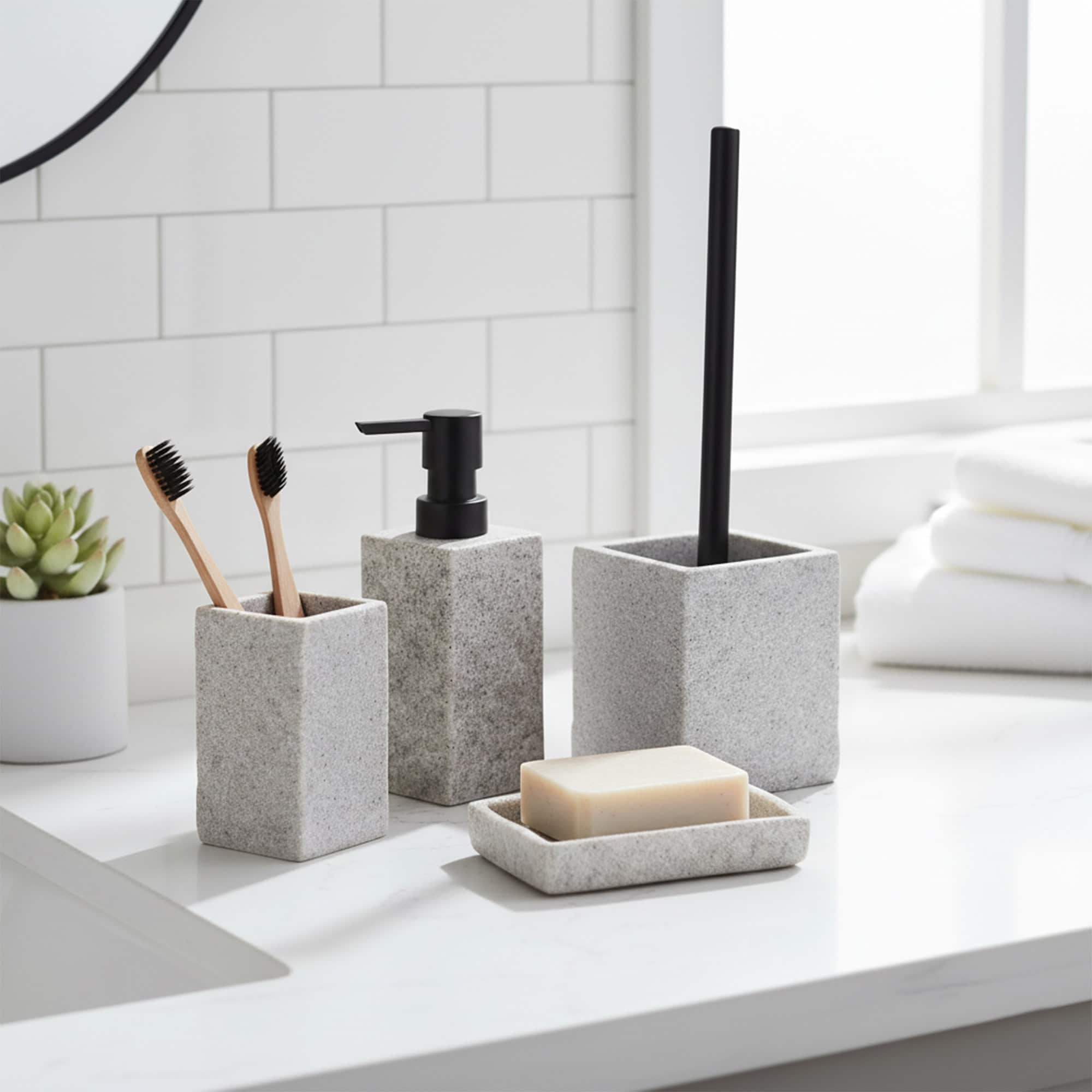 Gray stone-effect bathroom accessory set with dispenser, tumbler, brush holder, and soap dish on countertop