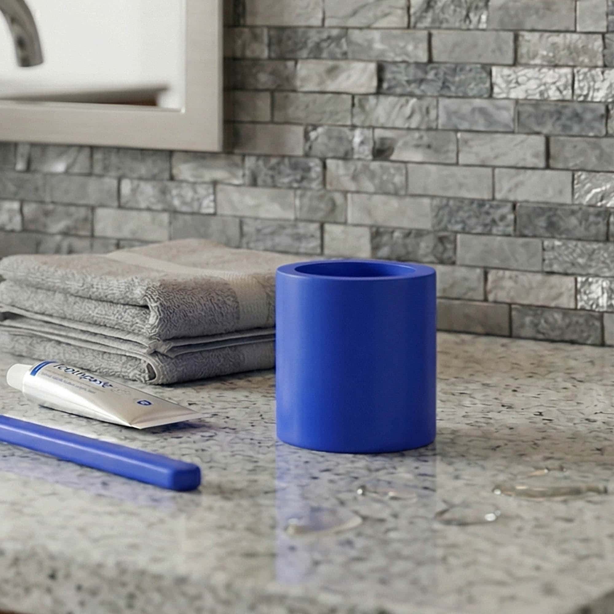 Blue bathroom tumbler holder on countertop with towels and toothbrush
